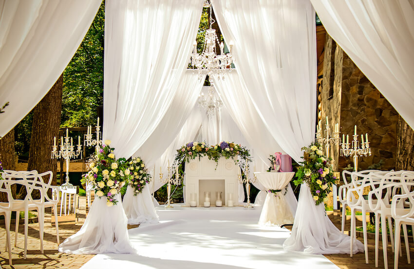 Outdoor wedding setting with chandeliers and white drapery